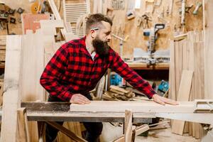 Woodworker focuses on crafting a wooden piece in a well-equipped workshop during daylight hours photo