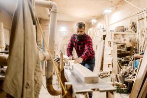 Craftsman operates woodworking machinery in workshop during daylight hours photo