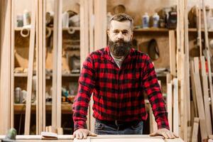 Skilled carpenter working in a well-equipped workshop surrounded by wood materials and tools photo