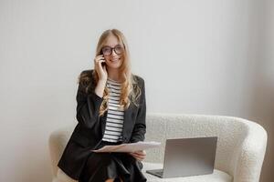 Businesswoman engages in a phone conversation while sitting on a couch in a modern office setting photo
