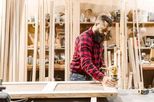Skilled carpenter using a router to craft wooden panels in a well-equipped workshop environment photo