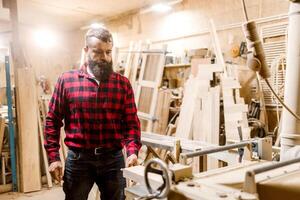 Skilled carpenter working in a workshop surrounded by wood and tools during the day photo