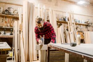 Carpenter working diligently in a woodworking shop on a rustic project surrounded by timber photo