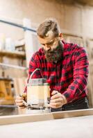 Carpenter working with wood router in workshop during daylight hours photo