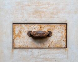 Close up of a rusty drawer handle on a wooden cabinet photo