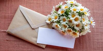Daisies arranged beside an envelope on a textured surface. photo