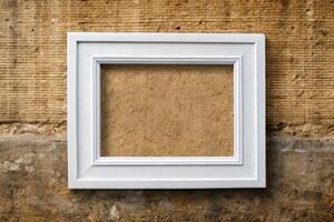 An empty white picture frame against a rustic wall. photo