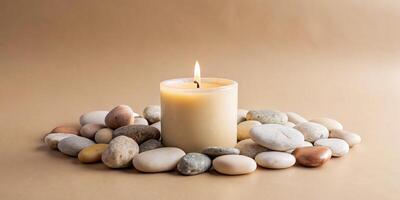 A lit candle surrounded by smooth pebbles on a table. photo