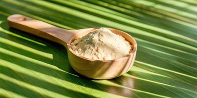 Wooden scoop on a green leaf background filled with powder. photo