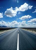 Long open road leading towards a horizon filled with fluffy clouds. photo