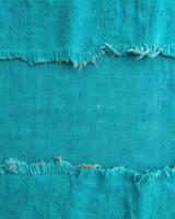 Vibrant turquoise fabric with frayed edges on display. photo