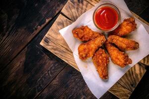 Crispy Chicken Wings with Ketchup on Rustic Wooden Tray photo
