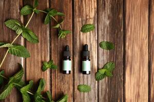 Natural Essential Oils with Fresh Mint Leaves on Wood photo