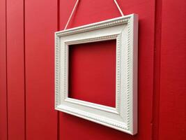 Empty White Picture Frame Against Vibrant Red Wooden Wall photo