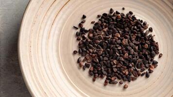 Raw cocoa beans on a rustic ceramic plate. photo