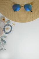 Summer vacation mood layout lifestyle spa or wellness concept with beach accessories and copy space. Top view flat lay background, including straw hat, sunglasses, seashells and pebbles photo