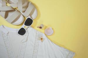 Summer travel vacation mood layout lifestyle spa or wellness concept with beach accessories and copy space. Top view flat lay background, including sunglasses, sandals and white tunic photo