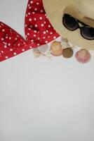 Summer travel vacation mood layout lifestyle spa wellness concept with beach accessories and copy space. Top view flat lay background, including straw hat, sunglasses, red swimsuit, seashells, pebbles photo
