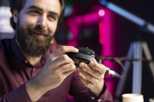 Close up of joyful influencer endorsing wireless mouse from sponsor, showing functionalities. Excited internet star promotes computer peripheral from partnering brand to followers on social media photo
