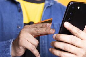Young person with man bun adding payment method on shopping website, entering credential and confirming money transfer after shopping online against orange background. Upbeat guy. photo