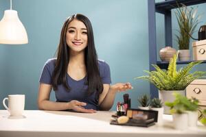 Cheerful beauty influencer presenting a makeup tutorial, creating content for her vlogging channel. Asian woman gestures with her hand while explaining the purpose of her during live broadcast. photo