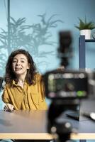 Focus on professional camera used by media star hosting online show in well lit studio, shooting vlog. Close up shot of high tech gear used by woman during live stream broadcast photo