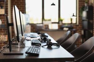 Empty workspace, with no person present, highlighting a modern business setting with desktop monitors. Multiple computers are neatly organized on desks in vacant brick wall office. photo