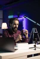 Tech expert assessing smartphone performance, talking about components used inside, doing unboxing . Entertainer unpacking mobile phone to review it on technology online channel photo