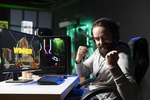 Exulting gamer excited after winning level in first person shooter, killing all enemies. Euphoric player celebrating, manifesting himself after being victorious in videogame photo
