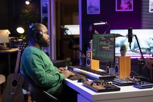 Audio engineer working on editing old recordings in home studio, mixing and mastering on digital software. Young producer operating on stereo console and equipment, music industry. photo