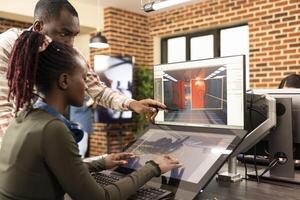 African american coworkers discussing innovative ideas at office desk, using graphic software for website development. Black male manager points to screen, explaining digital tools to female employee. photo