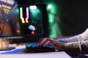 Man relaxing by playing cyber science fiction FPS videogame on PC at computer desk late at night. Close up of gamer shooting enemies with lasers bullets in online multiplayer first person shooter photo
