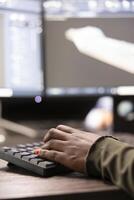 Closeup of african american person typing, inputting data into computer, improving geometry of digital machinery tool. Selective focus of black individual using keyboard and working on a cad software. photo