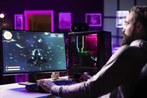 Man having fun by using gaming keyboard to fly spaceship in SF videogame, unwinding at home. Gamer using powerful PC and computer peripherals to play game, entertaining himself photo