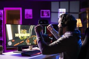 Esports player playing videogames in front of subscribers during livestream, celebrating after winning online match. Pro gamer streaming game for viewers, feeling happy after beating opponent photo