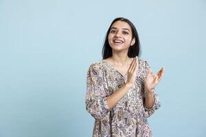 Confident pleased woman applauding in front of the camera and cheering for success, standing ovation for personal achievement. Indian girl ecstatic in admiration clapping hands in studio. photo