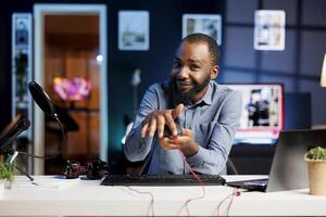 BIPOC internet show host filming review of newly released gaming led lights mouse in personal studio. Media star giving viewers feedback about computer peripheral performance photo