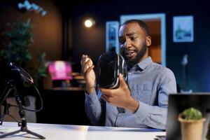 Tech content creator filming technology review of newly launched VR glasses, trying it and giving his impressions to audience. Internet star checking out virtual reality device photo