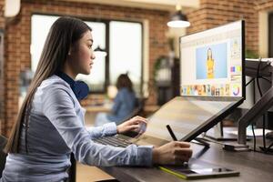 Professional female illustrator using stylus pen on graphics tablet, creating digital sketch. Asian woman working in creative agency workspace, focused on editing and designing content for production. photo