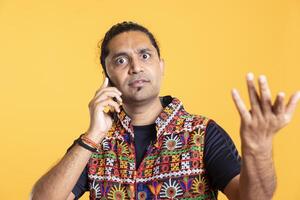 Portrait of dumbstruck man confused about friend over stupid arguments in debacle, studio background. Perplexed person in disagreement with mate, rejecting his arguments during telephone call photo