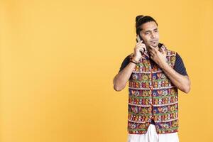 Overthinking man talking with friend on phone, doing stroking chin gesture during brainstorming. Pensive person discussing with mate during call, thinking, studio backdrop photo