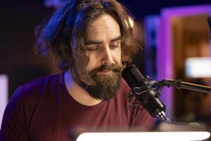 Talented musician producer singing a new song on microphone in home studio, composing music an creating tunes with piano keyboard and daw software. Artist works with electronic equipment. photo