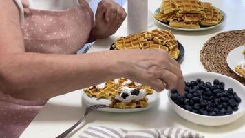 Chef garnishing waffles with blueberries and whipped cream video