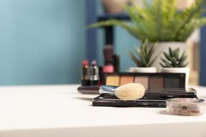 Selective focus on a brush placed on a white table along with other cosmetic products. A well organized beauty studio setup featuring a neatly arranged desk with makeup, brushes, and mini plants. photo