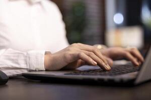 Female employee typing vital information on personal computer in office, with selective focus on her fingers to emphasize the precision involved in her task. Closeup of a person using laptop keyboard. photo