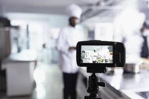 African american chef teaches his audience cooking skills on a , explaining preparation methods and plating techniques. Expert hosting virtual classroom for online culinary training. photo