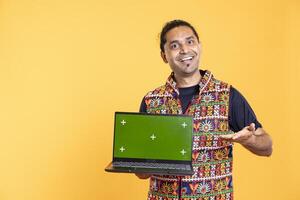 Portrait of influencer smiling while presenting green screen laptop, studio background. Upbeat content creator smiling while holding chroma key notebook used for advertising brands photo