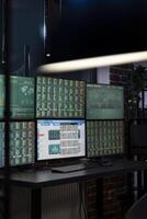 Vacant workstation with multiple monitors displaying forex charts, arranged in a modern office for traders. Computer screens showing financial data, ready for night shift employees. photo