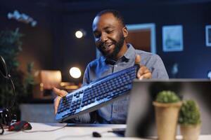 Content creator filming keyboard review in personal studio, pressing different buttons to show typing capabilities. Technology guru showcasing computer periperal to audience on niche online channel photo