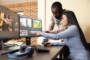 Skilled editors refining digital content using software in modern office. Asian and african american filmmakers enhancing footage quality on multi monitors, utilizing specialized editing tools. photo